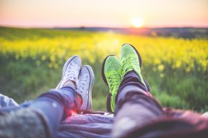 2 jeunes couchés dans l'herbe pour regarder un coucher de soleil